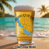 Glass of beer with "Chautauqua Lake NY" map design on a beach at sunset.