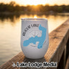 White insulated tumbler with Augur Lake New York map graphic resting on a wooden dock.