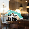 Aqua-colored graphic overlaying text "Rainbow" and "Life" on a window.