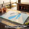 A glass cutting board featuring a blue map of Payette Lake and a compass design on a wooden table.