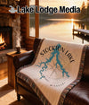 Fringe blanket with Stockton Lake map and compass on a leather sofa.