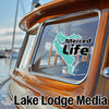 Merced Life sticker on a wooden boat window; Lake Lodge Media text below.