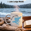 White mug with Squam Lake map and New Hampshire text, next to a book and scarf.