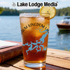 Glass of iced tea with lemon on wooden table, lake background, Lake Lodge Media logo.