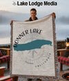 Man holds Donner Lake California throw blanket with compass design and fringed edges.