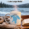 White mug with Lake Huron map graphic, steaming, by a window overlooking a lake.