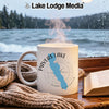 White mug with "Pavlas Lake Wisconsin" and compass design by a window.