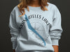 Light blue sweatshirt with "Skaneateles Lake" and compass, stylized lake shape.