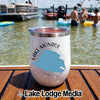 A white insulated tumbler with Lake Monroe branding sits on a wooden dock with boats and swimmers in the background.