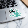 Lewisville Life sticker with turquoise lake map overlay on laptop keyboard.