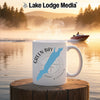 White mug with Green Bay Wisconsin map and compass design on a lake at sunrise.