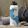 White water bottle with blue lake graphic and compass, next to rolled towel and bag.