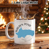 White mug with "Walden Pond Massachusetts" map design near fireplace and Christmas tree.