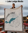Blanket with Cedar Lake map design and compass rose detail, held by a man.