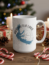 White mug with blue Arkabutla Lake outline and compass on wooden surface with festive decorations.