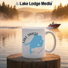 White mug with Lake Simcoe map and compass, on wooden surface with lake background.