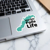 Turquoise outline sticker with "marble falls Life" text on a laptop.