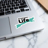 Turquoise map sticker with "Huntington Life" text on a laptop.