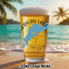 Glass of beer with American Lake map and compass graphic on a beach.