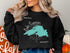 Black sweatshirt with a teal outline map of Lake Superior and "ONTARIO" text.