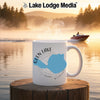 White mug with Glen Lake Michigan map and compass design on wooden surface by lake.