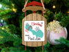 Sled ornament with "Merry Christmas FROM Pearl Lake" text hangs on tree.