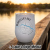A white insulated wine tumbler with Wheeler Lake Alabama branding, resting on a wooden dock at sunset.