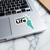 Cascade Life sticker on a laptop with a turquoise lake outline.