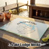 A rectangular glass cutting board with a compass and Fontana Lake map design on a wooden table.