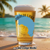 Glass of beer with Tribaldilake and British Co. text on a beach.