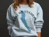 Light blue sweatshirt with Lake Willoughby, Vermont map and compass design.