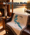 Woven blanket with Rainy Lake, Minnesota map and compass design on a leather couch.