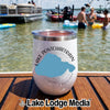 A white travel tumbler featuring Lake Pontchartrain, Louisiana, sits on a wooden boat deck with people swimming in the lake.
