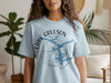 Light blue t-shirt featuring a compass graphic with a lake outline and text "Lake Greeson Arkansas".
