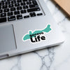 Teal sticker with "geneva Life" text sits on a laptop.