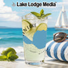 Glass of bubbly drink with lime, mint, and compass design on beach background.
