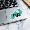 Teal sticker with "Mendenhall Life" text placed on a laptop keyboard.