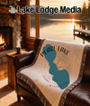 Blanket with Pearl Lake shape, compass, and "Wisconsin" text on a sofa.