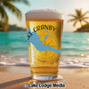 Glass of beer with Lake Granby outline and compass on a beach.