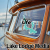 Walloon Life sticker on a wooden boat window and Lake Lodge Media text.
