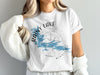 White t-shirt with Rainy Lake, Minnesota map and compass graphic.