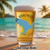 Glass of beer with "Siskiyou" and a blue map silhouette on a beach.