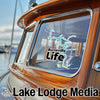 Burnsville Life sticker on a boat window, with Lake Lodge Media logo below.