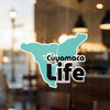 Cuyamaca Life logo on a teal background with black text, reflecting a building interior.
