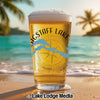 Beer glass with "Flagstaff Lake" and a compass design on a beach.