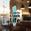 Turquoise and black "Mosquito Creek Life" sticker on a window.