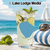 Glass of lemonade with lime and mint on a beach with a sailboat in the background.