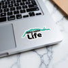 Sticker with turquoise map shape and "Merwin Life" text on laptop.