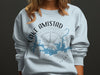 Light blue sweatshirt with Lake Amistad map logo and compass design.