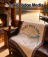 Woven blanket with Fort Peck Lake map and compass design on a sofa.